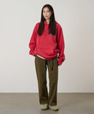 Model wearing bark pigment colored Gramicci Women's Brooks Pants and a red hoodie on a light-tone background.