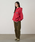 Model wearing bark pigment colored Gramicci Women's Brooks Pants and a red hoodie on a light-tone background.