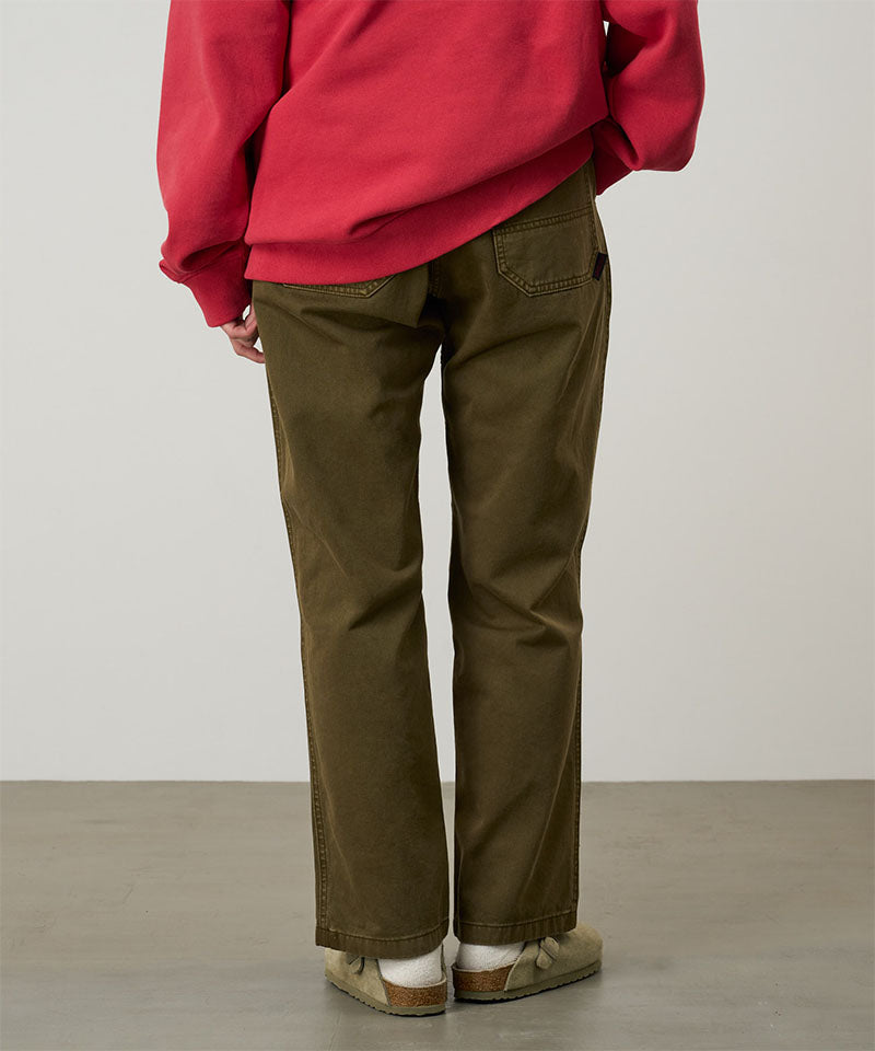 Back view of a model wearing bark pigment colored Gramicci Women's Brooks Pants and a red hoodie on a light-tone background.