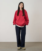 Model wearing double navy Gramicci Women's Brooks Pants and a red hoodie on a light-tone background.