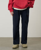 Model wearing double navy Gramicci Women's Brooks Pants and a red hoodie on a light-tone background.