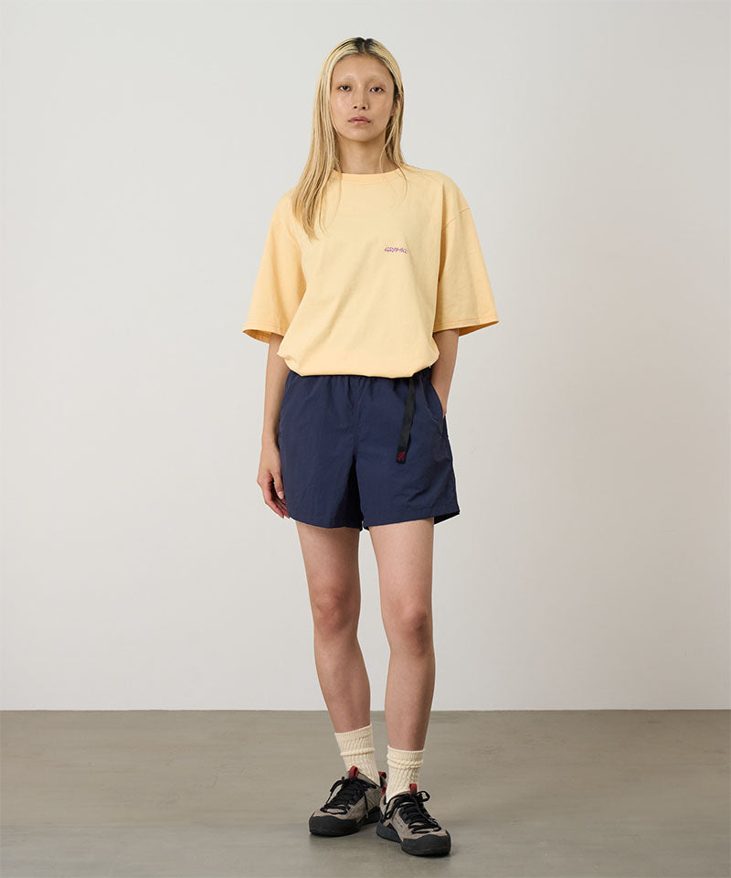 Model wearing british navy Gramicci Women's Nylon Active Short and a yellow shirt on a light-tone background.