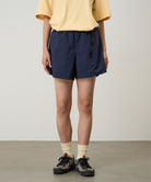 Model wearing british navy Gramicci Women's Nylon Active Short and a yellow shirt on a light-tone background.