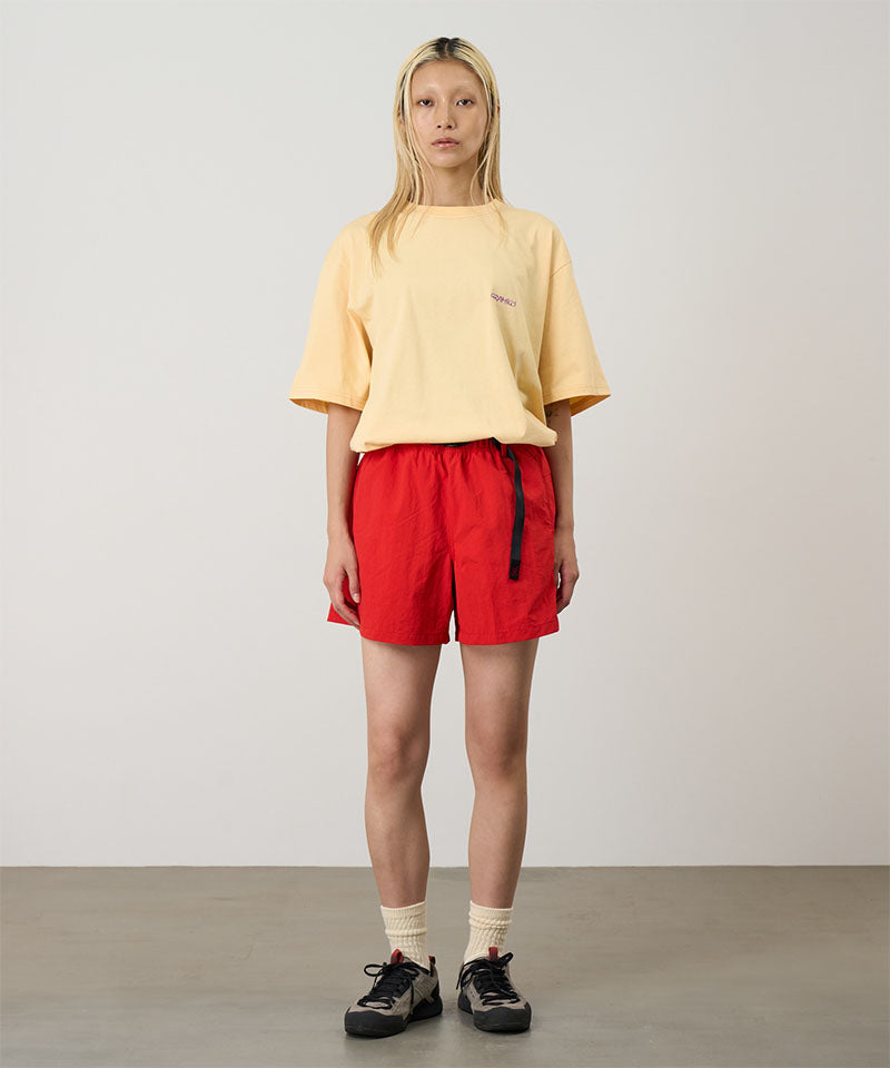Model wearing burnt orange Gramicci Women's Nylon Active Short and a yellow shirt on a light-tone background.
