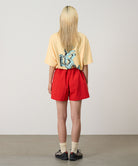 Back view of a model wearing burnt orange Gramicci Women's Nylon Active Short and a yellow shirt on a light-tone background.