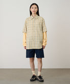Model wearing beige Gramicci Women's Corduroy Utility Short and a green plaid shirt on a light-tone background.