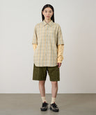 Model wearing olive Gramicci Women's Corduroy Utility Short and a green plaid shirt on a light-tone background.