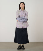 Model wearing a black Gramicci Nylon Utility Skirt and plaid shirt on a light-tone background.