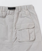 Close-up view of an ecru colored Gramicci Nylon Utility Skirt back pocket on a light-tone background.
