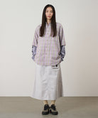 Model wearing a ecru colored Gramicci Nylon Utility Skirt and plaid shirt on a light-tone background.