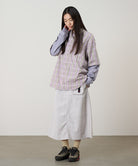 Model wearing a ecru colored Gramicci Nylon Utility Skirt and plaid shirt on a light-tone background.