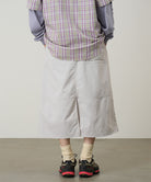 Back view of a model wearing a Gramicci ecru colored Nylon Utility Skirt against a light-tone background.