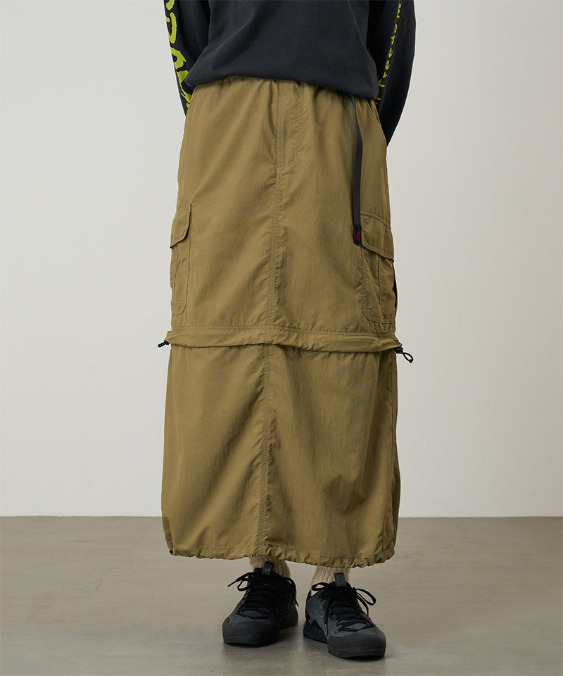 Model wearing a Gramicci Convertible Cargo Skirt in the color khaki and a black shirt on a light-tone background.