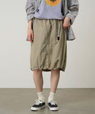 Model wearing a Gramicci milk tea colored Nylon Packable Midi Skirt against a light-tone background.