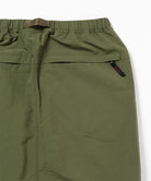 Close-up view of a olive Gramicci Nylon Packable Midi Skirt pocket on a light-tone background.
