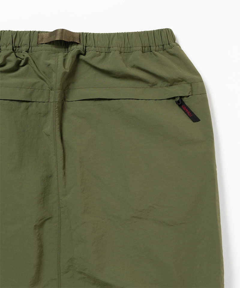 Close-up view of a olive Gramicci Nylon Packable Midi Skirt pocket on a light-tone background.