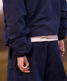 Man wearing a navy blue Gramicci rain jacket and pants with a blurred background
