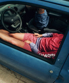Person reclined inside a blue car.