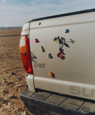 Back of an off-white SUV with Gramicci rock climbing magnets in a desert setting.