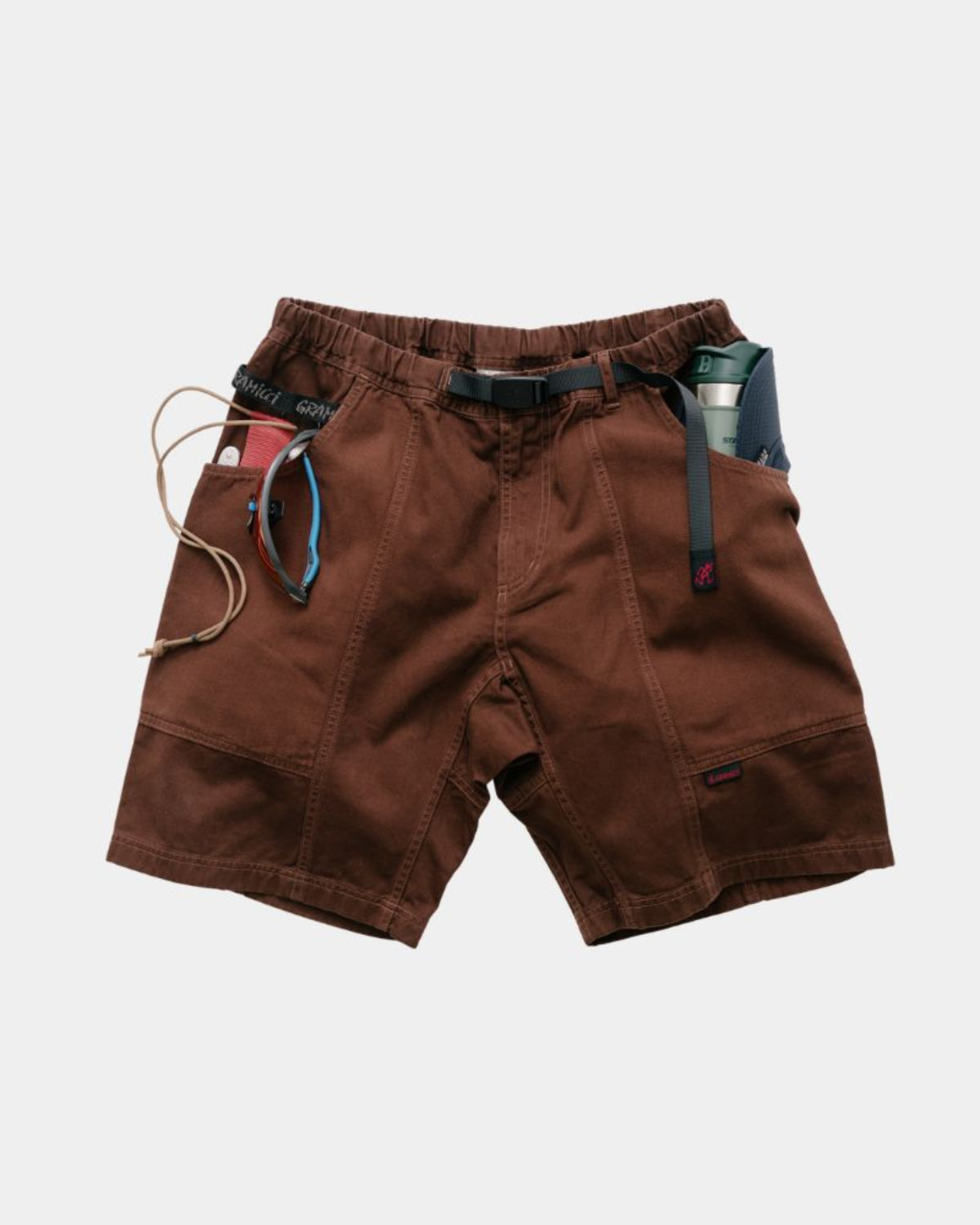 Brown gadget shorts with multiple pockets and a signature Gramicci belt on a light gray background